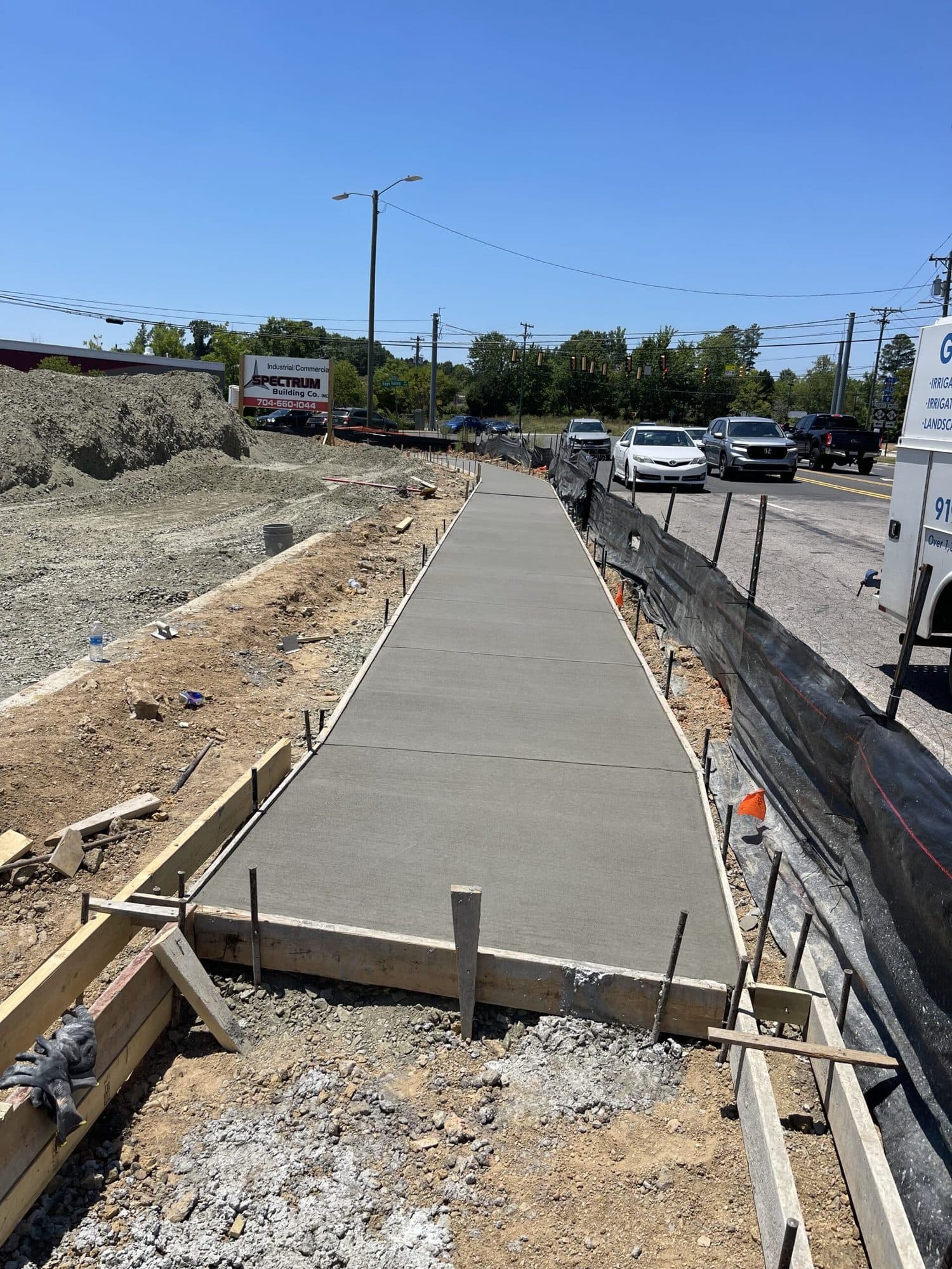 Freshly poured concrete sidewalk still in its forms alongside a public road
