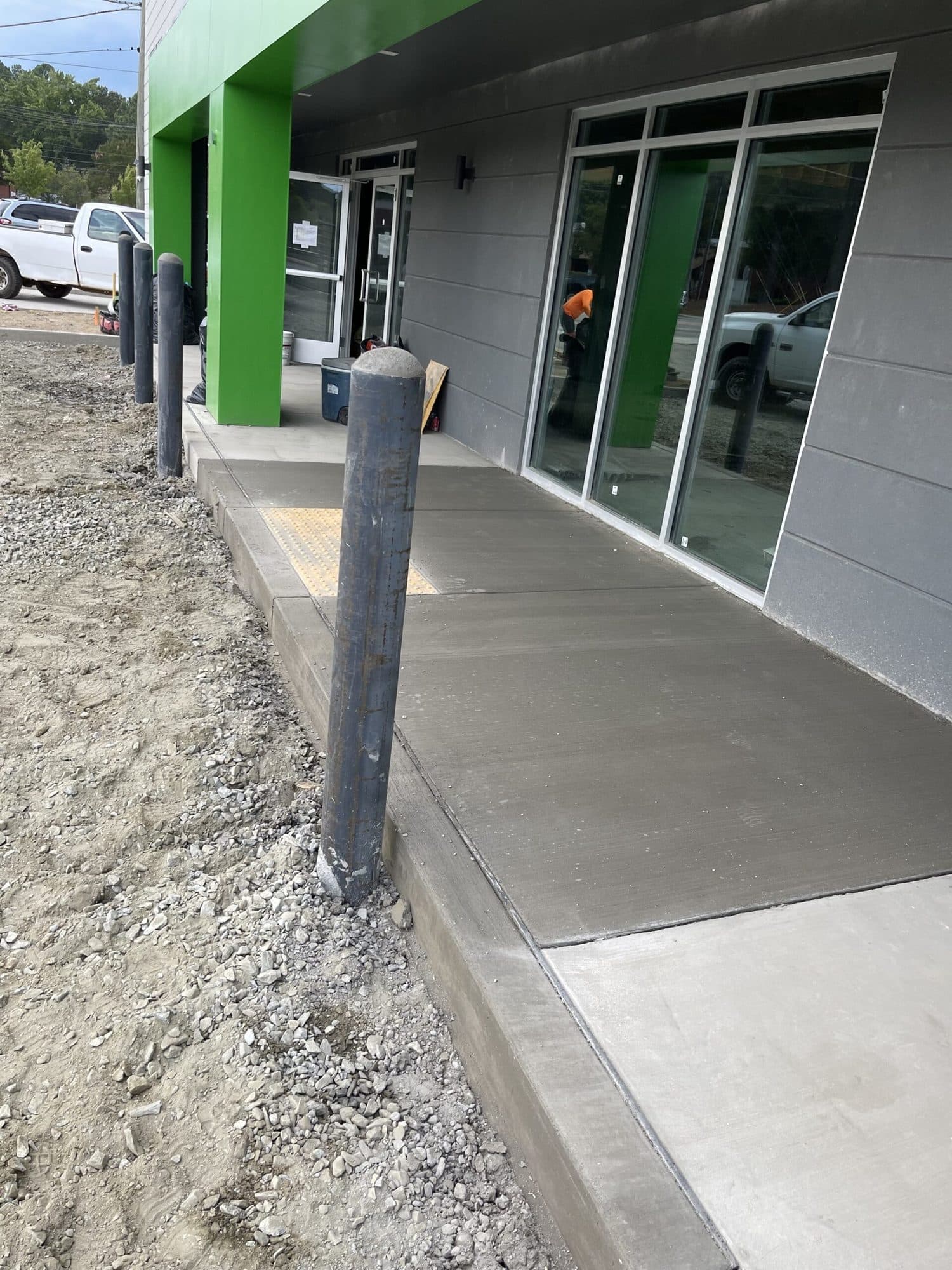 Finished concrete walkway with bollards at a storefront entrance