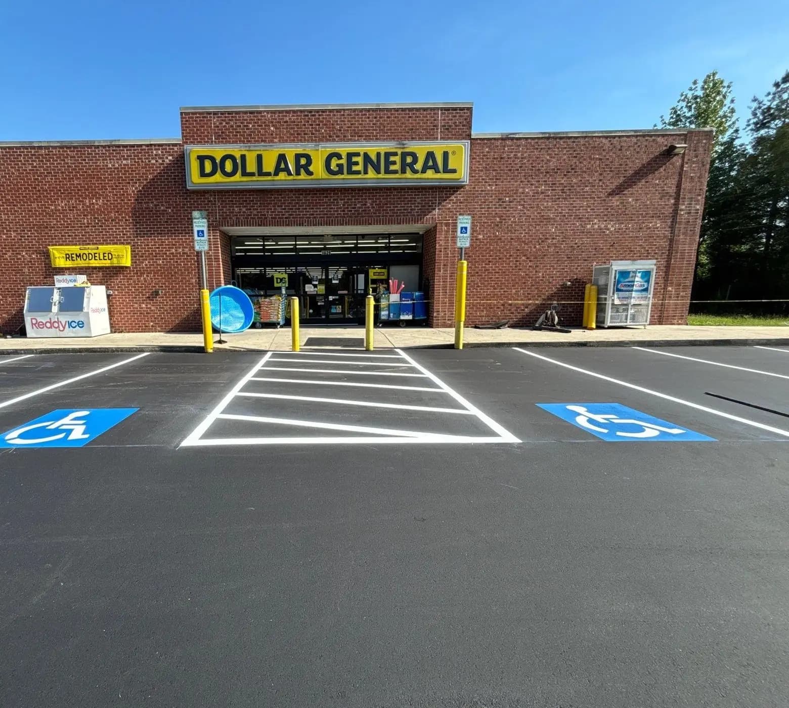 Yellow bollards and accessible parking signage at a Dollar General storefront in Monroe NC