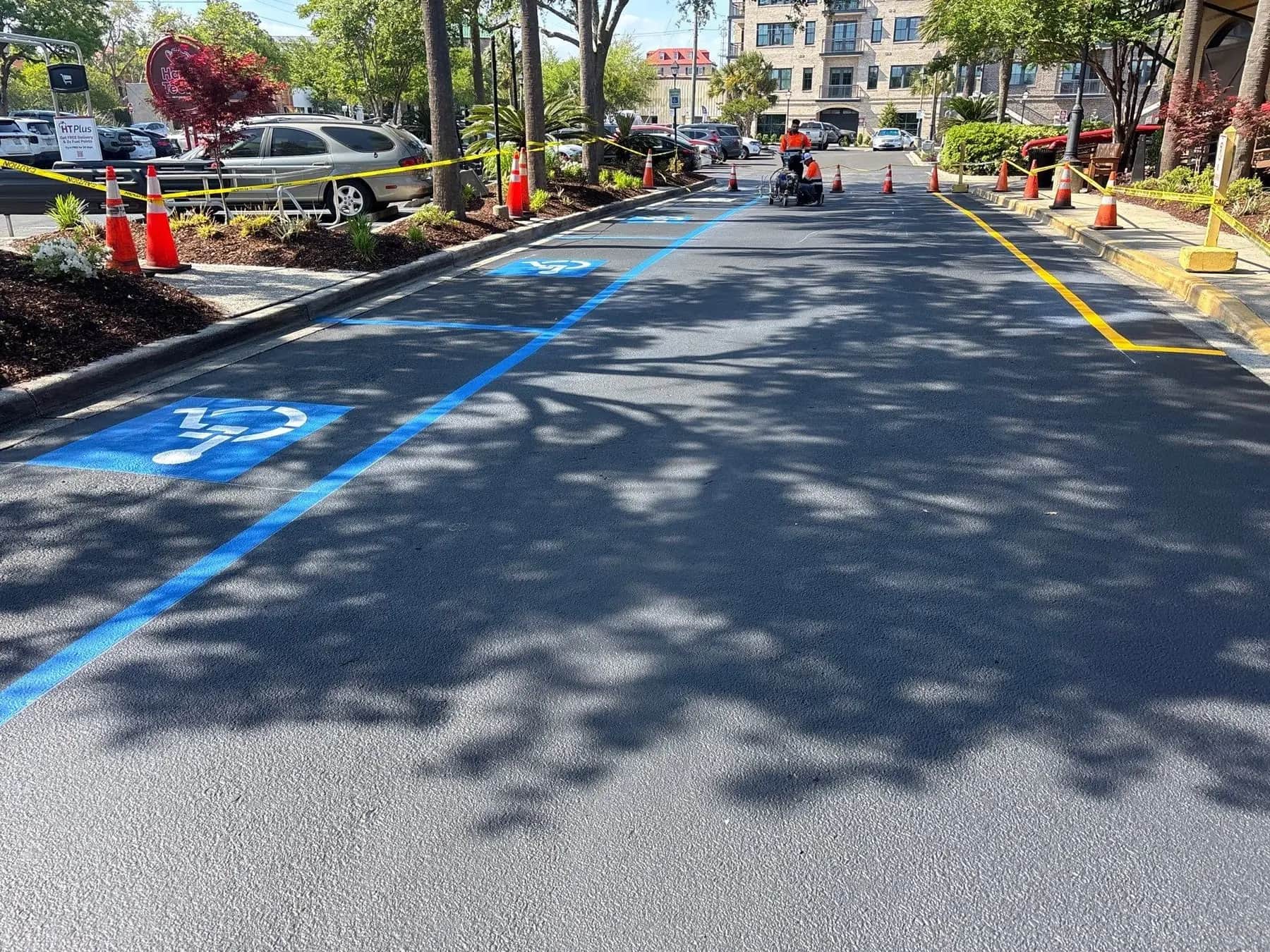 Crown Paving crew striping blue accessible stalls and a hatched access aisle at Harris Teeter in Charleston, SC