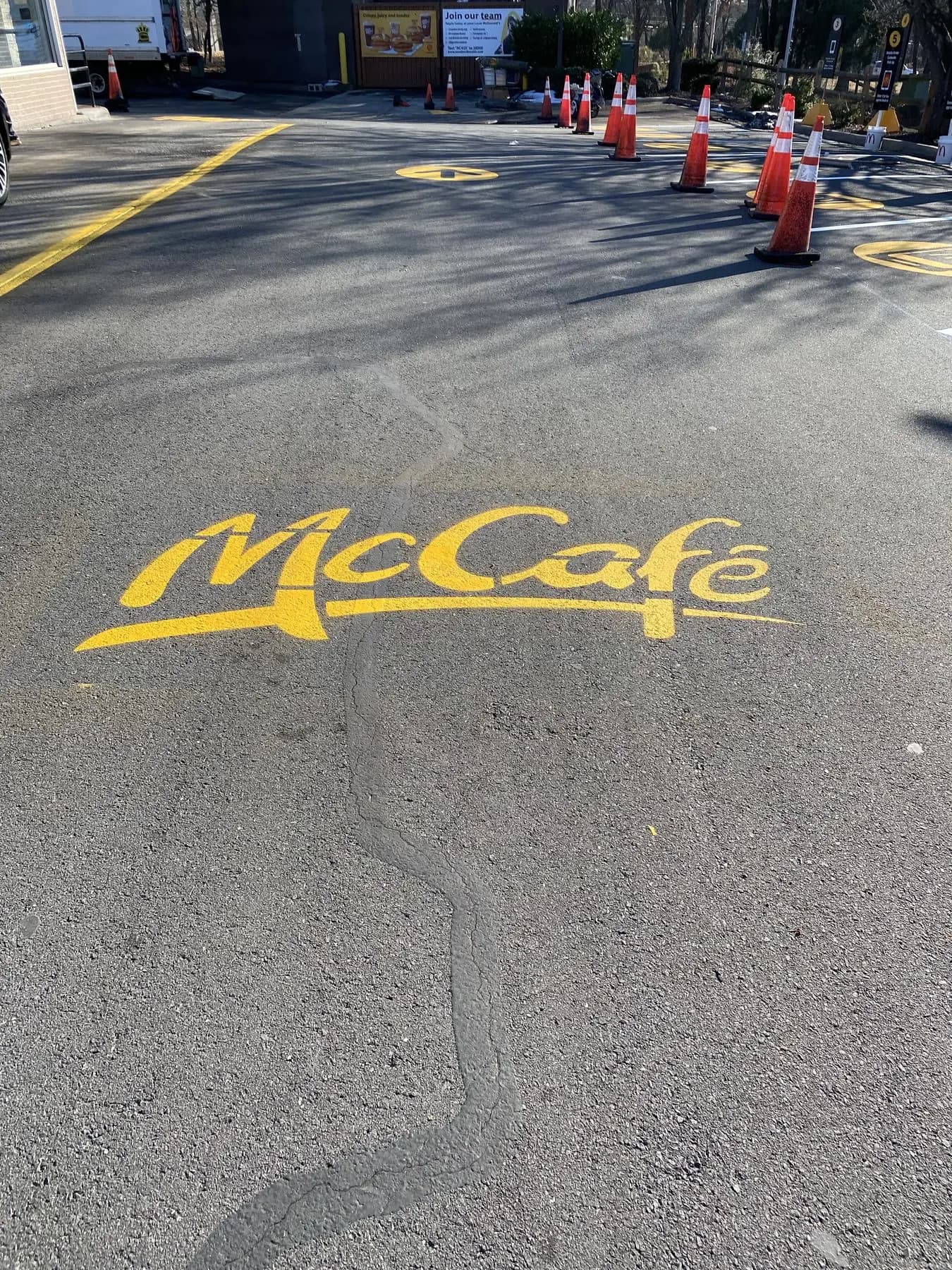 A McCafe brand stencil painted in yellow on a resurfaced drive lane