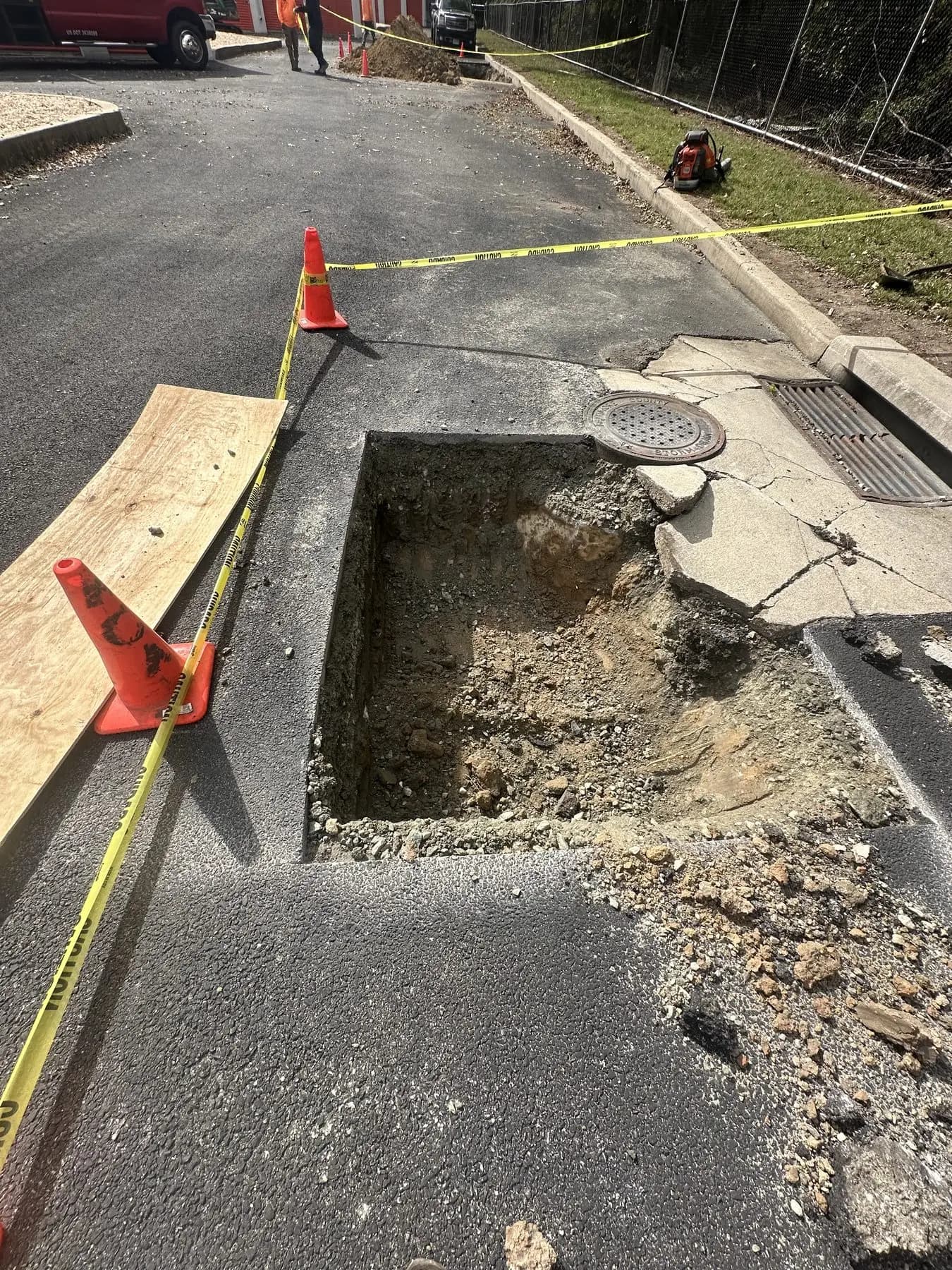 A sinkhole opened up in the pavement beside a drain inlet, excavated for repair