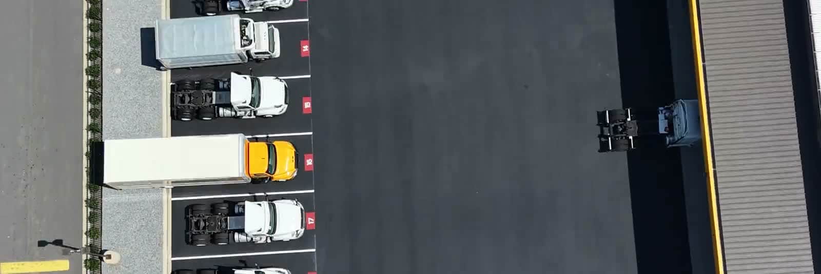 Aerial view of a completed truck yard, trailers backed into the docks on fresh asphalt