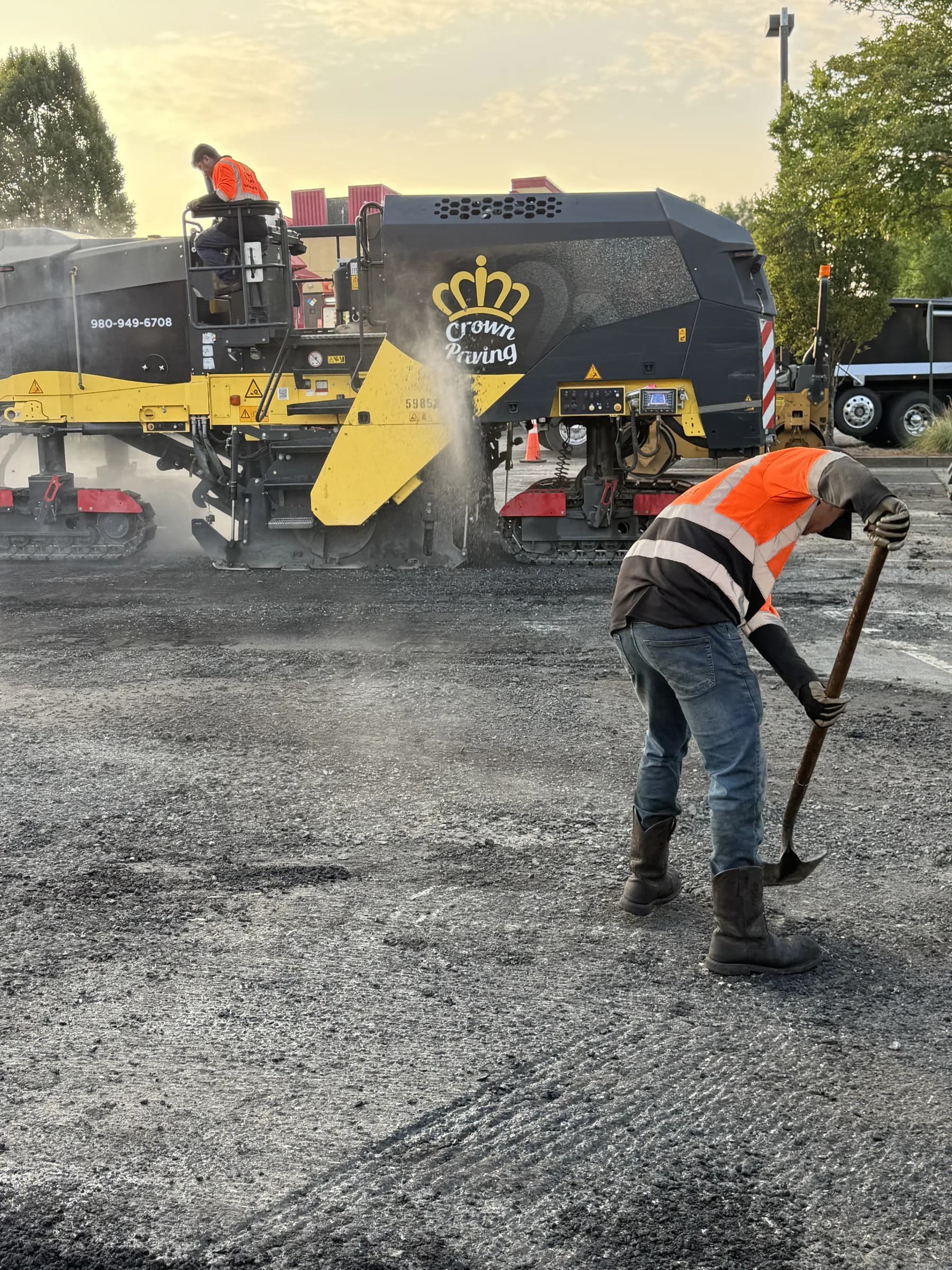 Milling machine cutting the worn surface at Northeast Plaza at golden hour