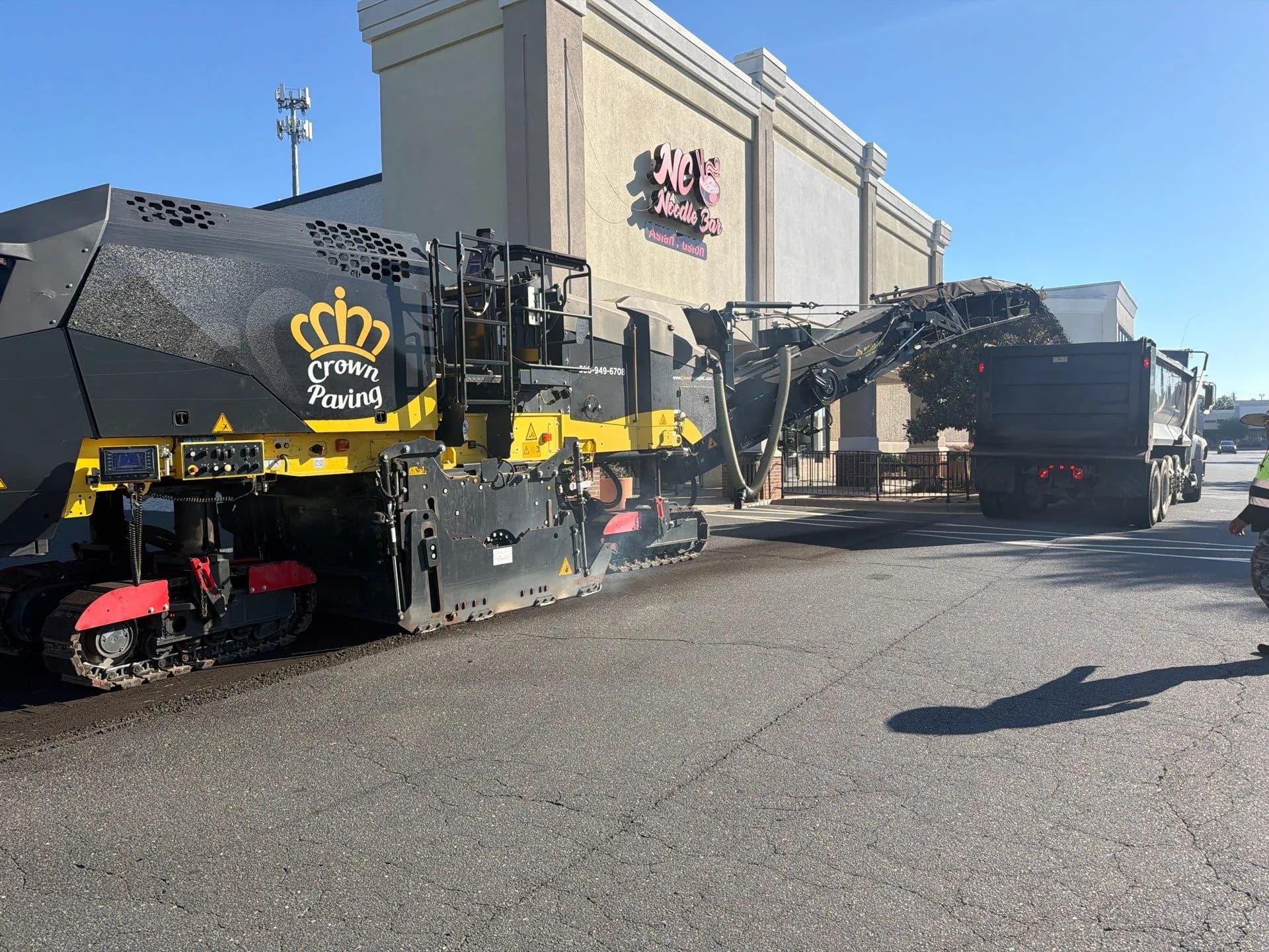 Crown Paving milling machine cutting out worn asphalt and loading the millings into a haul truck