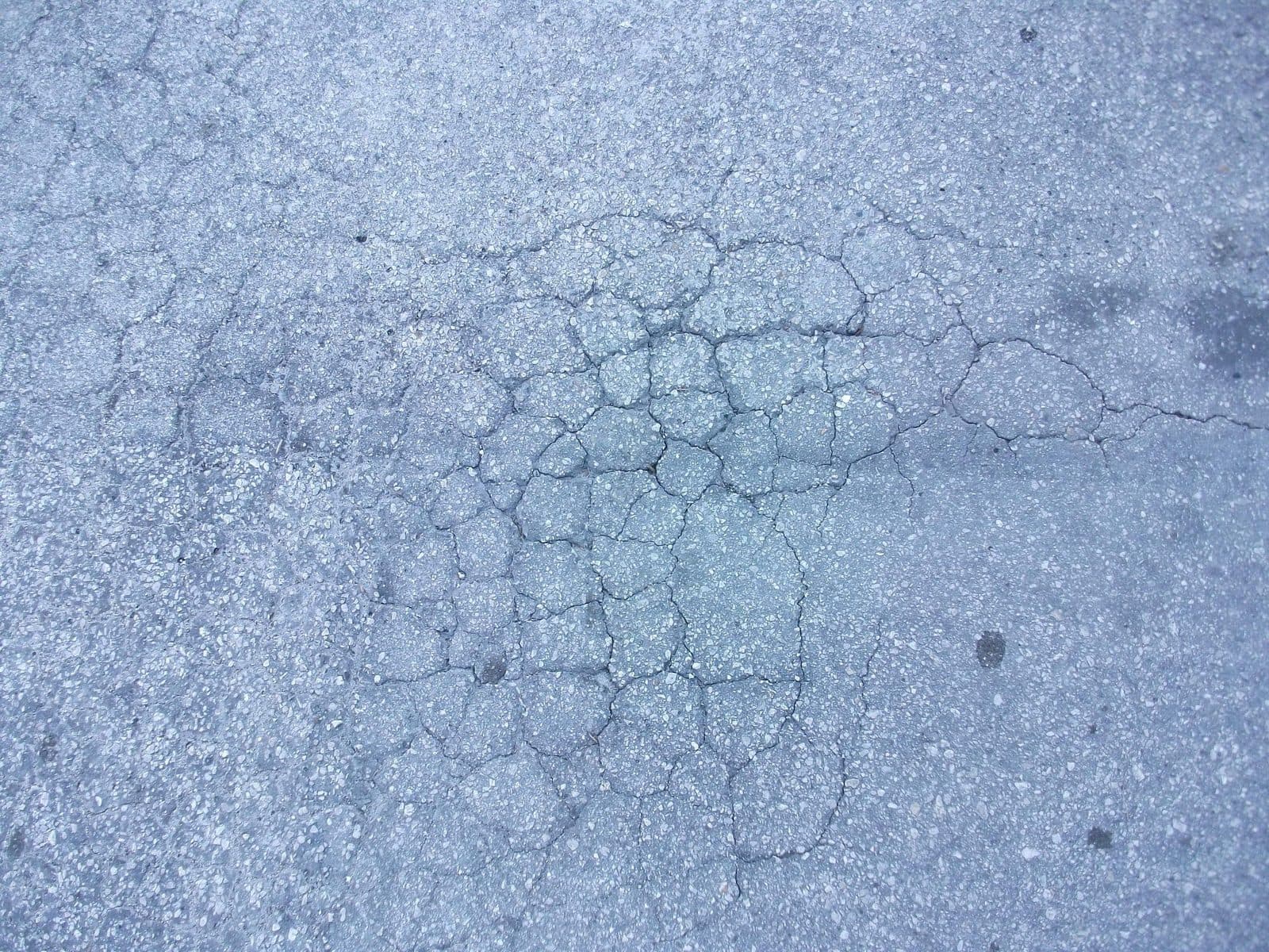 A patch of interconnected cracking spreading through an otherwise intact asphalt surface