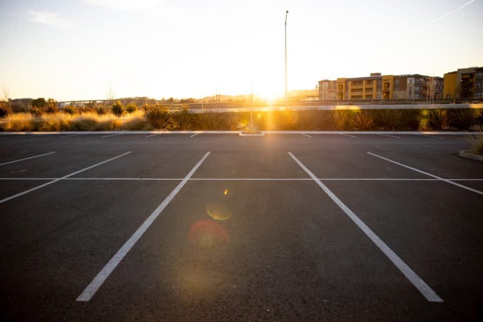 An empty parking lot with crisp white stall markings, lit by low evening sun