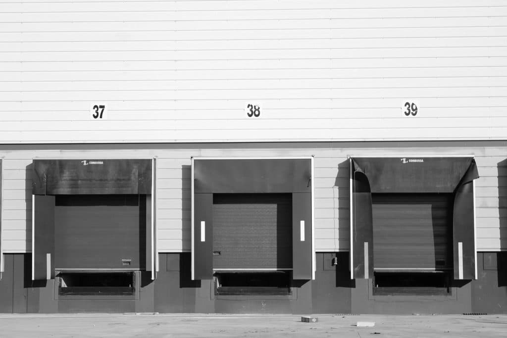 Three numbered loading dock doors above the concrete truck apron of a distribution warehouse
